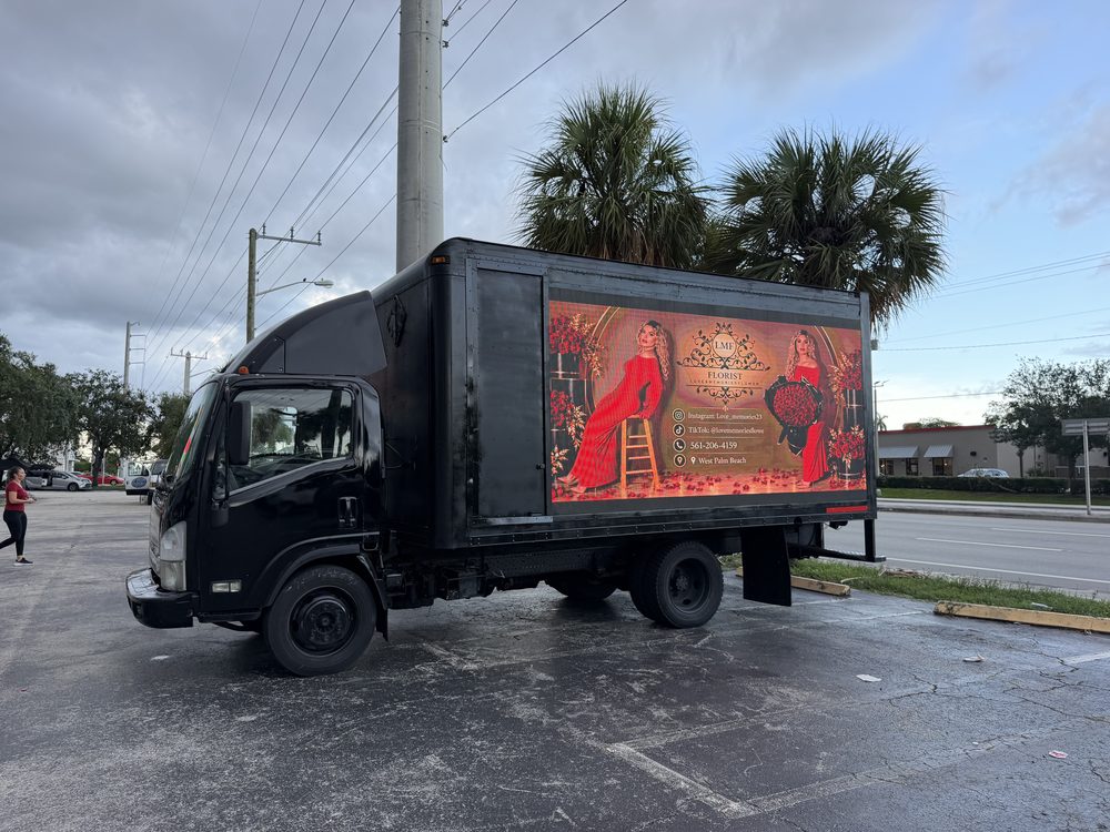 Black box truck seen from the driver side, cab and full-length LED screen visible, parked in a lot